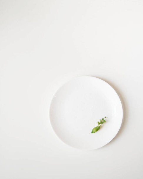 White background with a white plate on which there is a small pod of peas. - Foto, afbeelding