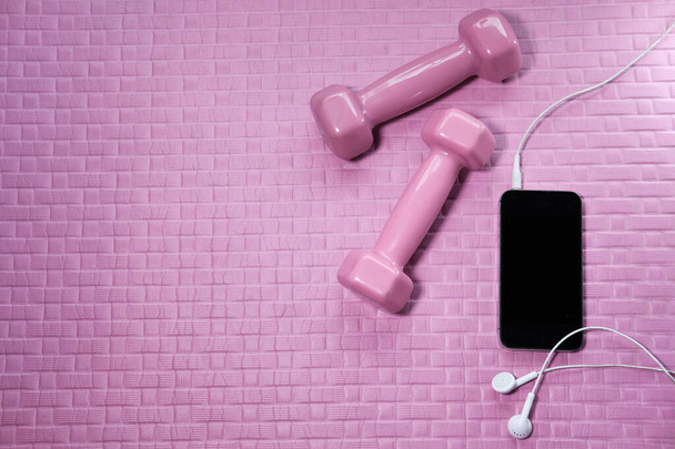 телефон и гантели на коврике для упражнений
 - Фото, изображение