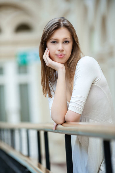 Portrait of young beautiful woman with long hair near wooden railing. - Фото, зображення