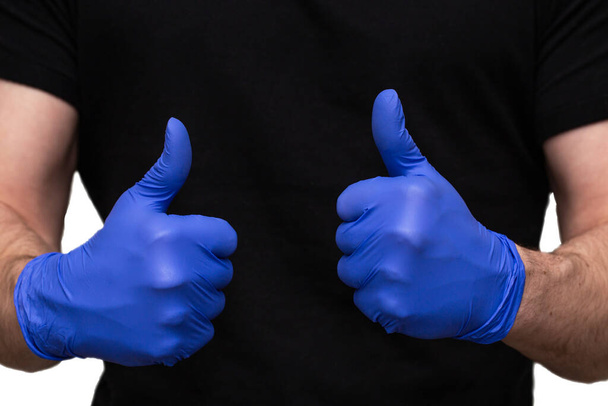 Persona con guanti di lattice blu per la protezione coronavirus con i pollici in su, Covid-19 auto isolamento o quarantena a casa di supporto medici e infermieri
 - Foto, immagini