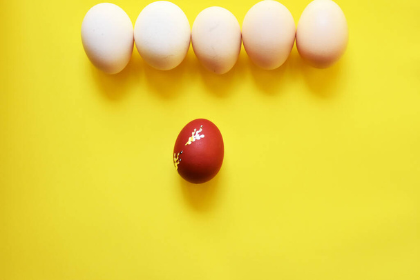 Ovos de Páscoa brancos no fundo amarelo com um ovo na cor vermelha
 - Foto, Imagem