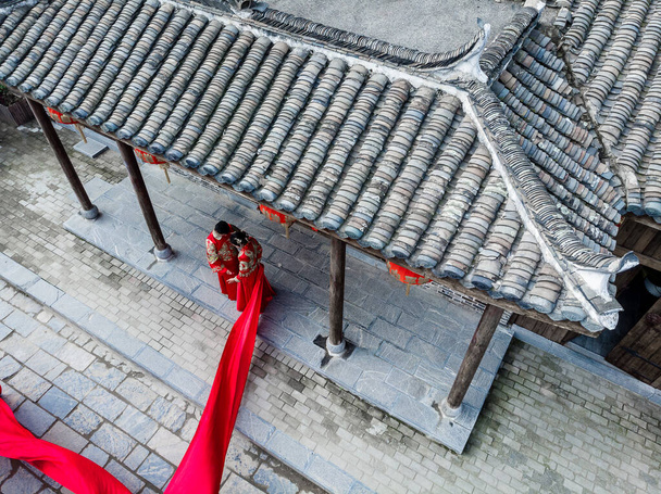 Пара в традиционных китайских свадебных костюмах позирует для фото
 - Фото, изображение