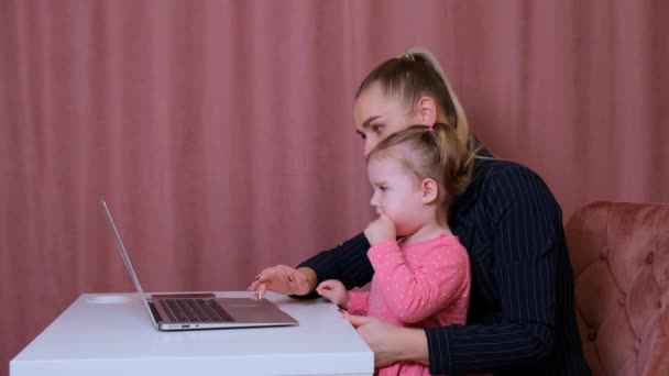Working mom works from home office. Happy mother and daughter smiling. Successful woman and cute child using laptop. Freelancer workplace. Female business. It is not easy but she is up to the task - Footage, Video