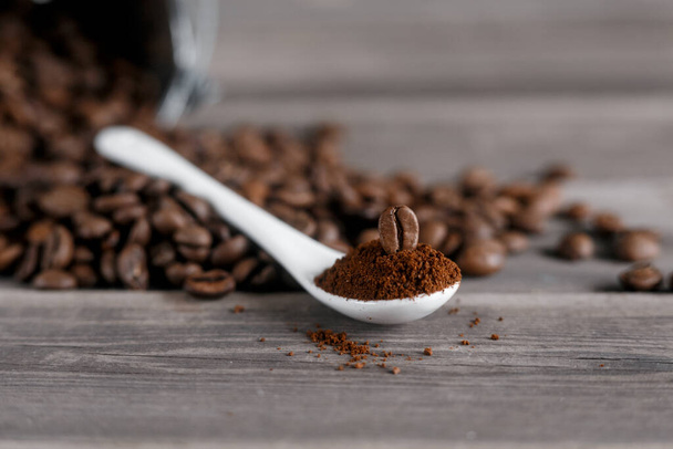  white ceramic spoon with ground coffee on a wooden background Fried Arabica grains  - 写真・画像
