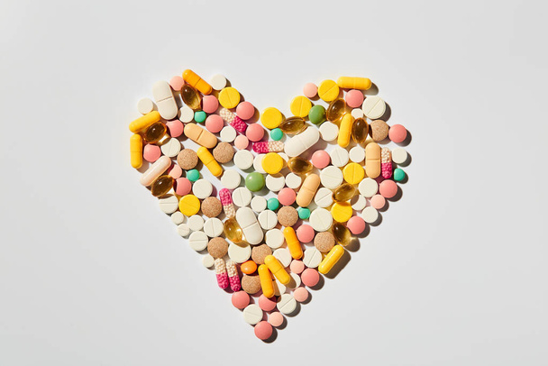 Colorido assorted coração em forma de pílulas padrão flat lay de pílulas de medicina medicina colorida no fundo branco. Conceito de saúde
 - Foto, Imagem
