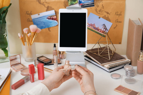 Makeup artist at table with modern tablet computer and cosmetics - Photo, image