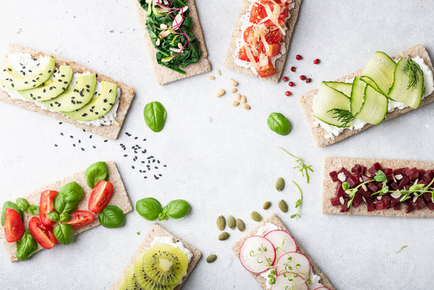Different kinds of vegetarian sandwiches on a light background. Top view, place for text. - Zdjęcie, obraz
