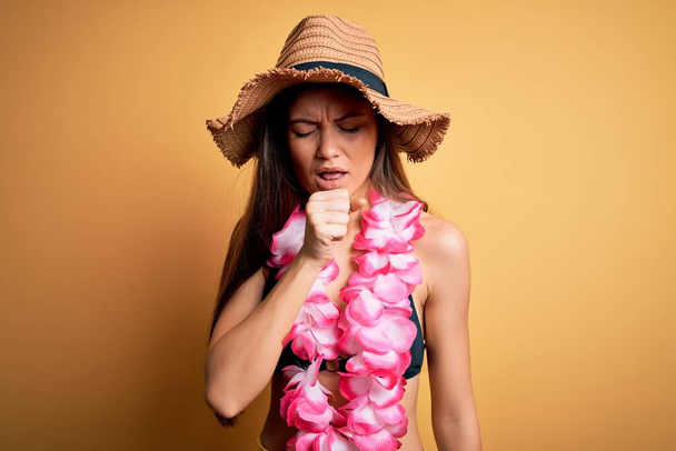 Giovane bella donna con gli occhi azzurri in vacanza indossando bikini e lei hawaiana sensazione di malessere e tosse come sintomo di freddo o bronchite. Concetto sanitario
. - Foto, immagini