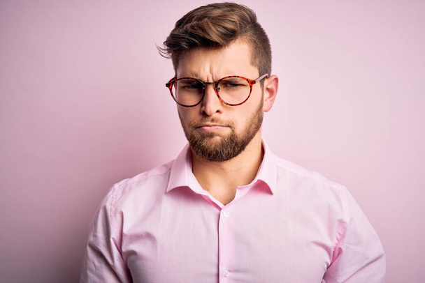Young handsome blond man with beard and blue eyes wearing pink shirt and glasses depressed and worry for distress, crying angry and afraid. Sad expression. - Foto, Imagen