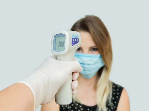 Gebruik van infrarood contactloos voorhoofd thermometer pistool om de lichaamstemperatuur te controleren op virus covid-19 symptomen - Foto, afbeelding
