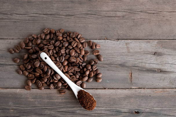  white ceramic spoon with ground coffee on a wooden background Fried Arabica grains  - Photo, Image