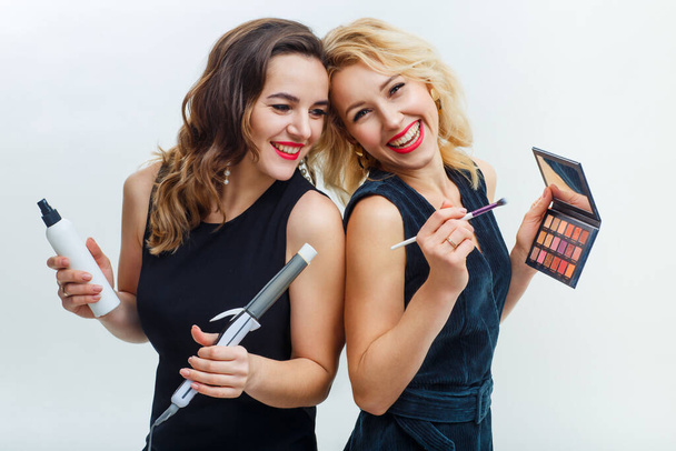 two girls in dark dresses with smiles on a white background. Makeup artist and stylist with his own working tools - Photo, Image