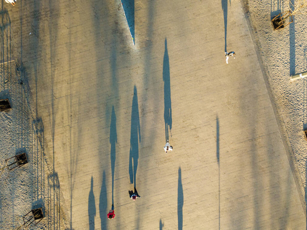 Vista aérea. Sombras de transeúntes en plaza en la mañana de otoño
 - Foto, Imagen