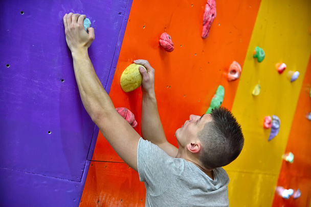 Climber on artificial climbing wall in bouldering gym without insurance. Extreme and healthy lifestyle concept. - Фото, изображение