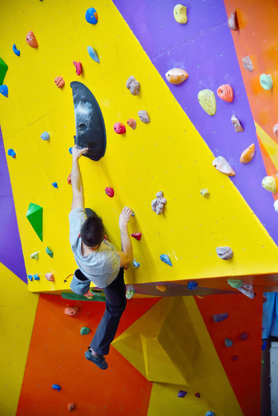 Man climbing up on practice wall indoor. Extreme and healthy lifestyle concept. - Φωτογραφία, εικόνα
