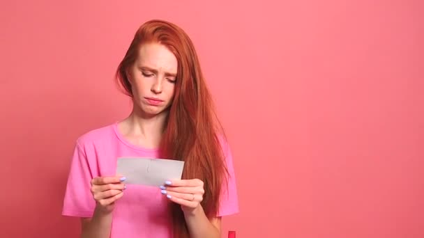 punatukkainen inkivääri nainen vaaleanpunainen studio tausta repiminen valokuva kortti hymyilevä kansainvälinen pari
 - Materiaali, video