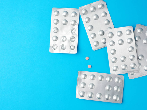 runde Pillen in Blisterverpackungen auf blauem Hintergrund, Kopierraum - Foto, Bild