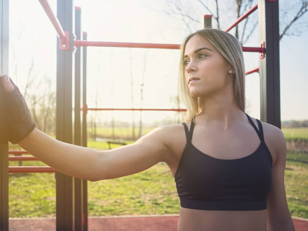 Young Athletic Woman in Sportswear Posing at Monkey Bars in the Park - Photo, Image