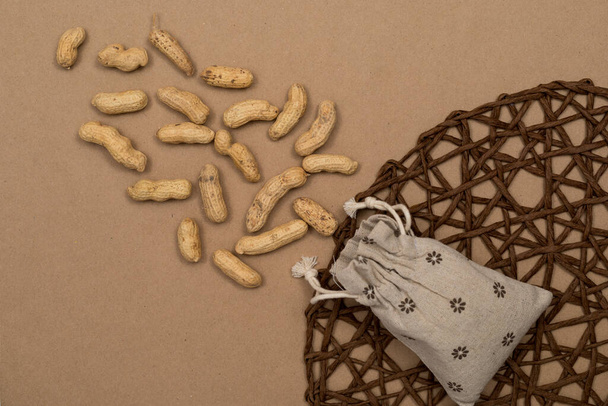 Noix, cacahuètes décortiquées, saupoudrer sur la table à partir d'un sac de lin, papier kraft fond. Vue de dessus avec copyspace, position plate
. - Photo, image