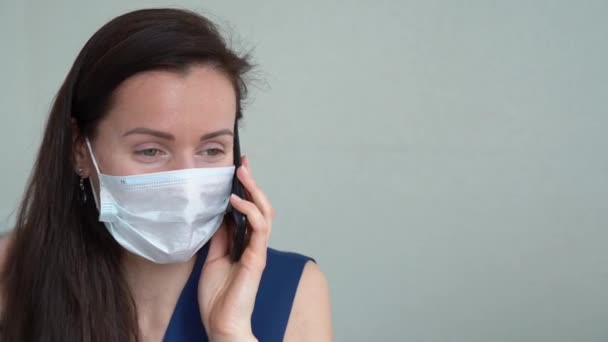 Wonderful sick young girl in blue clothes wear protective medical face mask, talk with her parents about her health on gray background close up. Woman getting better in isolation. Healing concept  - Séquence, vidéo