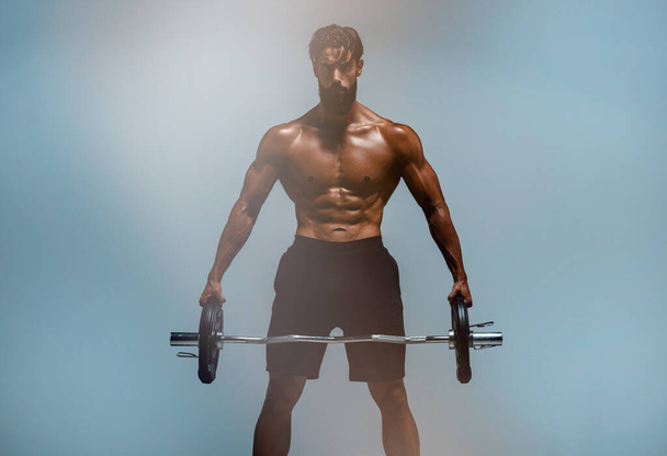 Knappe atletische mannen tillen gewichten - Foto, afbeelding