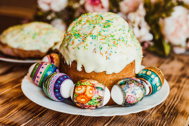 Glazed easter cake decorated with colored powder and with colorful eggs on wood background. Happy Easter Holidays.   - Fotó, kép