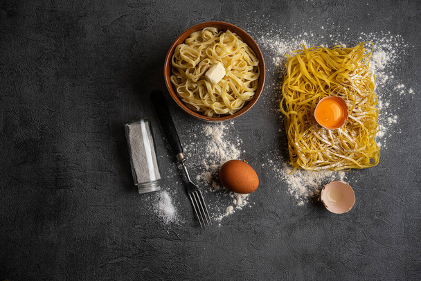 Still life with raw homemade pasta and boiled pasta and ingredients for pasta - Фото, изображение