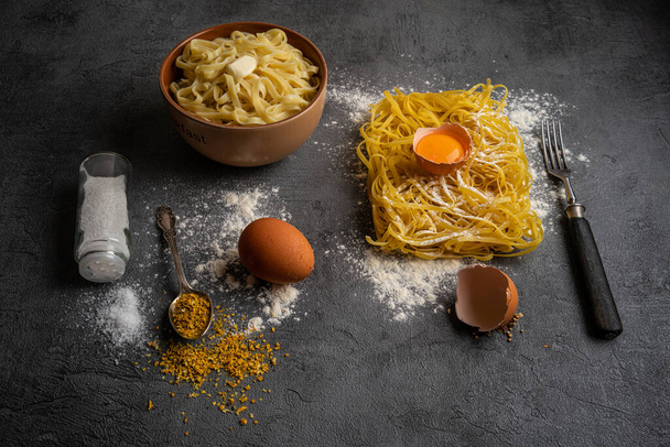 Fresh Italian pasta "Regionalle" with egg on dark surface with fresh raw egg in flour. Flat lay, close up. - 写真・画像