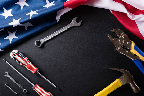 Happy Labor day concept. American flag with different construction tools on black table background, with copy space for text. - Photo, Image