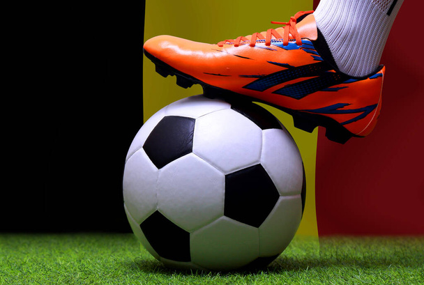 Zblízka nohy a nohy fotbalisty nebo fotbalisty chodit na zelené trávě připraven hrát zápas na národní Belgie vlajkové pozadí. - Fotografie, Obrázek