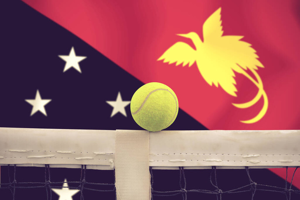 Tennis bal in net op vlag achtergrond. - Foto, afbeelding