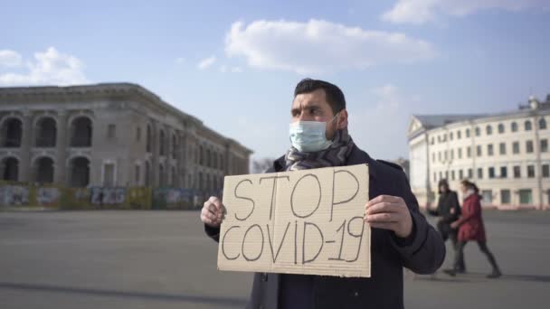  Man met medisch masker vragen om epidemie COVID 19 stoppen met poster op straat.  - Video