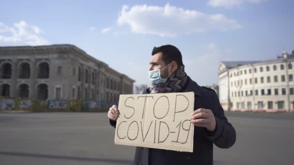 Pandemia del COVID19. Uomo in mascherina medica stand con poster sulla strada della città
.  - Filmati, video