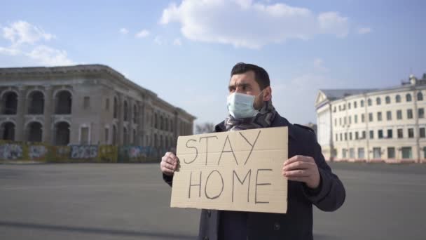 Világjárvány csapat. Orvosi maszkos férfi áll poszterrel a város utcáján..  - Felvétel, videó