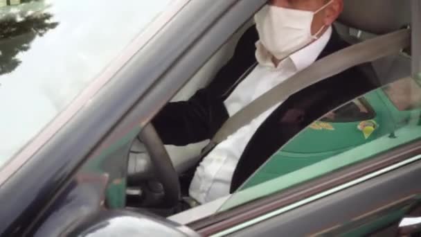 Sicherheitsmann misst die Körpertemperatur eines Fahrers im Auto mit Infrarot-Thermometer und erlaubt ihm, seinen Weg fortzusetzen - Filmmaterial, Video