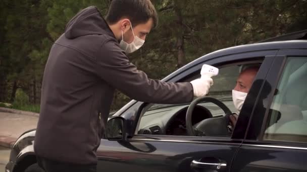 Sicherheitsmann misst die Körpertemperatur eines Fahrers und lässt ihn weiterfahren - Filmmaterial, Video