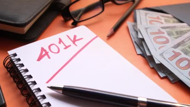 Κοντινό πλάνο της λέξης 401k στο σημειωματάριο με μετρητά, αριθμομηχανή στο φόντο χρώμα  - Πλάνα, βίντεο
