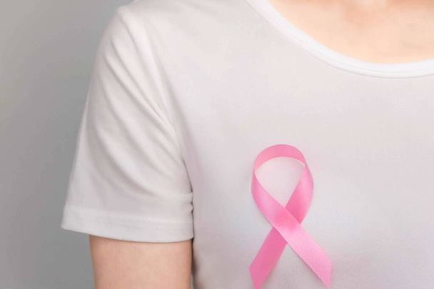 Concepto del Día Mundial del Cáncer de Mama, cuidado de la salud: la mujer llevaba una camiseta blanca, cinta rosa para concienciar sobre el cáncer de mama, un arco simbólico para crear conciencia sobre las personas que viven con la enfermedad del tumor de mama de las mujeres.
 - Foto, imagen