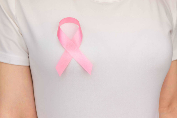 Παγκόσμια Ημέρα κατά του Καρκίνου του μαστού Concept, υγειονομική περίθαλψη - γυναίκα φορούσε λευκό t-shirt, ροζ κορδέλα για την ευαισθητοποίηση του καρκίνου του μαστού, συμβολικό χρώμα τόξο αυξάνοντας την ευαισθητοποίηση για τα άτομα που ζουν με την ασθένεια του όγκου του μαστού των γυναικών - Φωτογραφία, εικόνα