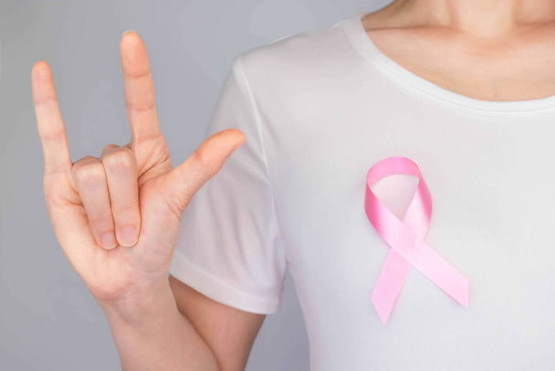 世界の乳癌の日の概念、健康管理-女性は乳癌の意識のための白いTシャツ、ピンクリボンを身に着けていた、女性の乳癌の病気と住む人々の意識を高める象徴的な弓の色 - 写真・画像
