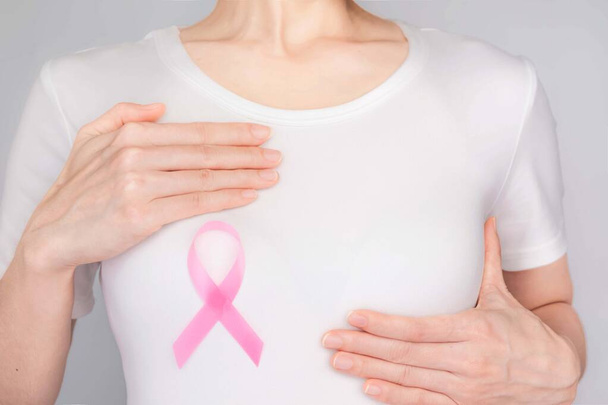 Concepto del Día Mundial del Cáncer de Mama, cuidado de la salud: la mujer llevaba una camiseta blanca, cinta rosa para concienciar sobre el cáncer de mama, un arco simbólico para crear conciencia sobre las personas que viven con la enfermedad del tumor de mama de las mujeres.
 - Foto, Imagen