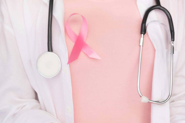 Концепция Всемирного дня рака молочной железы, здравоохранение - Розовая лента, стетоскоп, красное сердце для информированности о раке молочной железы, символический лук повышение осведомленности людей, живущих с опухолью молочной железы у женщин
 - Фото, изображение