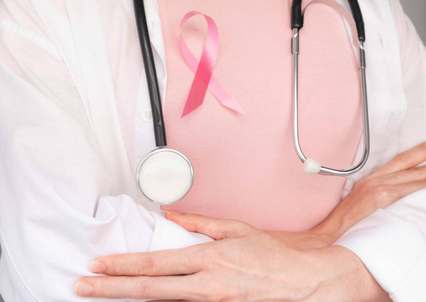 Konzept zum Welttag des Brustkrebses, Gesundheitsfürsorge - Pinkfarbenes Band, Stethoskop, rotes Herz für das Brustkrebsbewusstsein, symbolische Schleife zur Bewusstseinsbildung für Menschen, die an Brustkrebs erkrankt sind - Foto, Bild