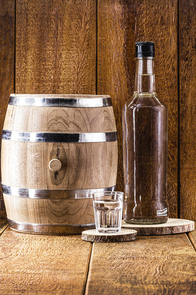 Old oak barrel and glass of high quality distilled alcohol. Brazilian silver cachaca, called pinga, vodka, white rum, liqueur, pure drink, Poitn, sake, brandy or Absinthe. - Photo, Image