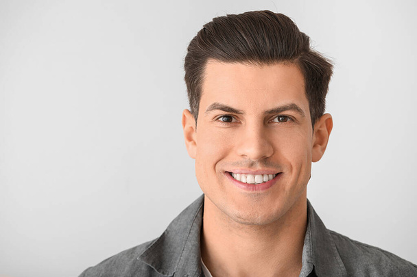 Junger Mann mit gesunden Zähnen auf hellem Hintergrund - Foto, Bild