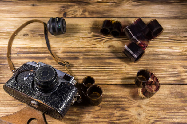 Retro photo camera with photo film and lens on wooden table - Photo, Image