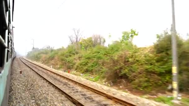 Az Indiai Vasút. Vasúti személyvonat. Az utolsó kocsi ablakából lőtték le, kanyarodó síneken. Indiai vasúti pálya, India. - Felvétel, videó