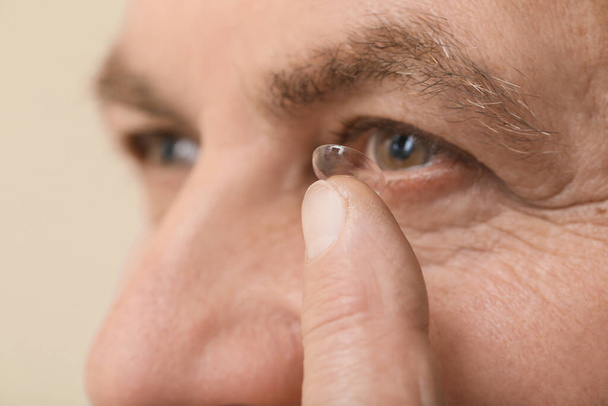 Volwassen man zet contactlenzen in, close-up - Foto, afbeelding