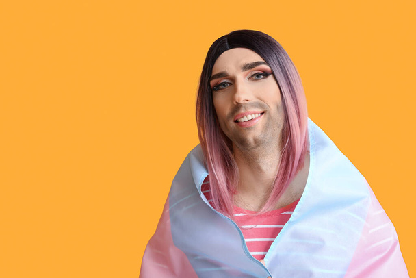 Портрет молодой трансгендерной женщины с флагом на цветном фоне
 - Фото, изображение