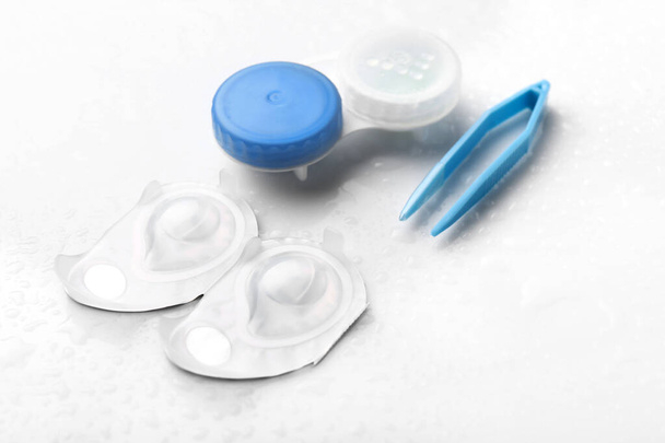Conteneurs pour lentilles de contact et pinces à épiler sur fond blanc
 - Photo, image